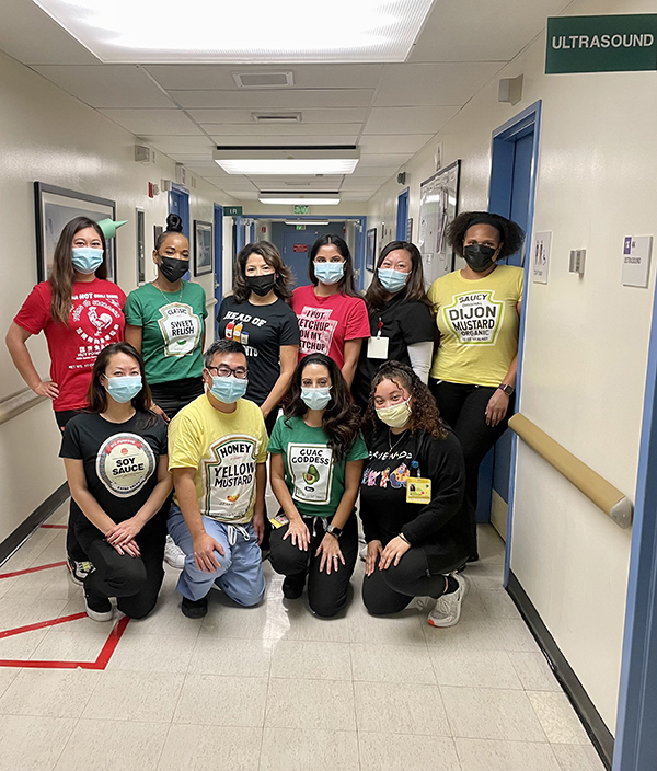 A group of people wearing costumes posing for a photo in the hallway of a hospital 