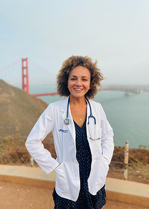 Headshot of a female UCSF medical student wearing a white lab coat with the Golden Gate bridge in the background
